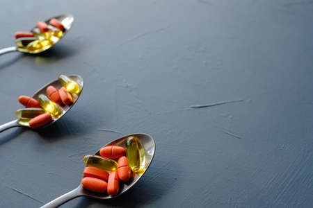 pills capsules in spoons. medication and illness cure. drugs on blue backgroundの写真素材
