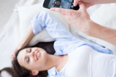 home photoshoot. man taking photos of his girlfriend in bedroom. couple leisure and pastime