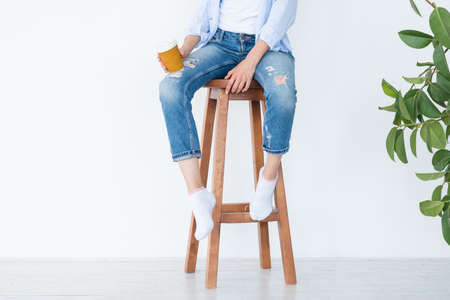 woman sitting on high wooden stool with coffee cup. relaxed leisure and casual lifestyle. white background.の写真素材