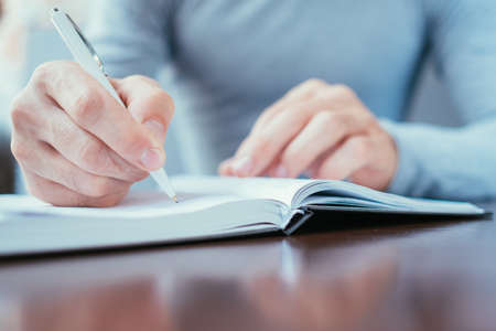 man hand writing in day planner. work schedule and personal organizer concept.の写真素材