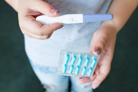 birth control pills. oral contraceptive. woman holding blister pack drugs and pregnancy test in handsの写真素材