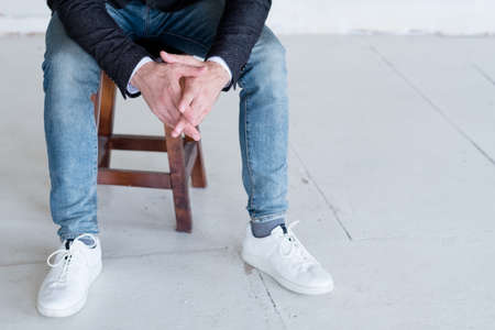 business trainer or consultant sitting on a chair. smart casual dress code. man in jacket and jeans. cropped shot.の写真素材