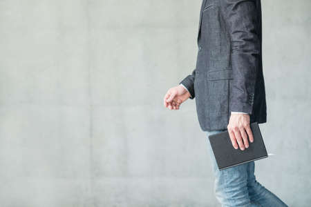 business man walking holding notebook in hand. smart casual fashion styleの写真素材