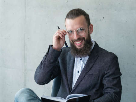smiling professor or examinator. bearded man in suit jacket rearranging his glassesの写真素材