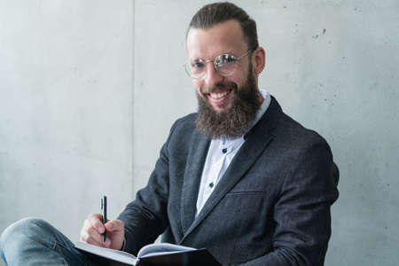 smiling psychologist counsellor or shrink writing in his diary during consultationの写真素材