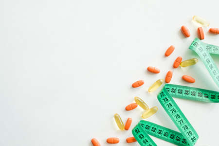 tape measure and diet pills. weightloss health and medicine concept. drugs on white backgroundの写真素材