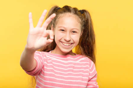 ok gesture. smiling adolescent girl. happy facial expression. emotional portraitの写真素材