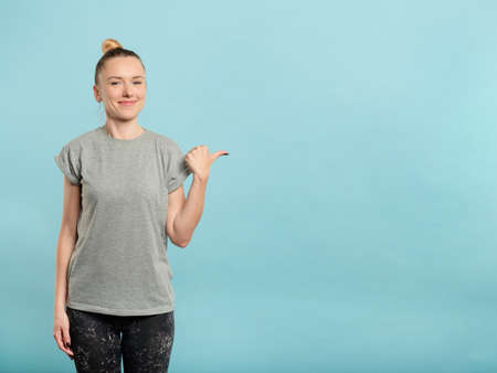 smiling woman pointing to empty space on the right. copy space for text or product placement on blue background.の写真素材