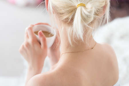backview of a woman holding coffee mug. tender tempting and sensual portrait.の写真素材