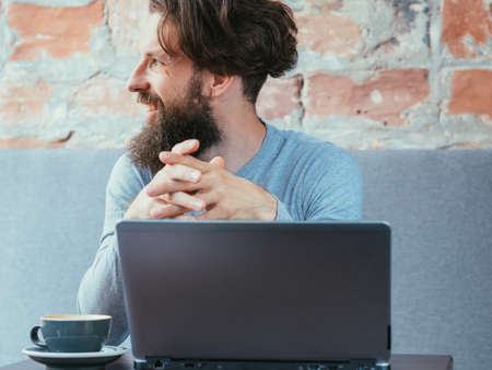 man sitting in cafe with laptop and coffee cup on the table. blogging and social media.の写真素材