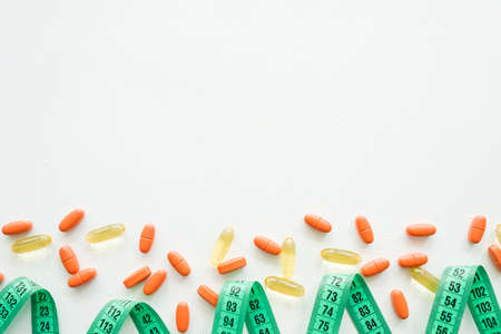 tape measure and diet pills. weightloss slimming and addiction. drugs on white background