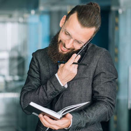 busy business man lifestyle. guy checking with his day planner and talking on the phoneの写真素材