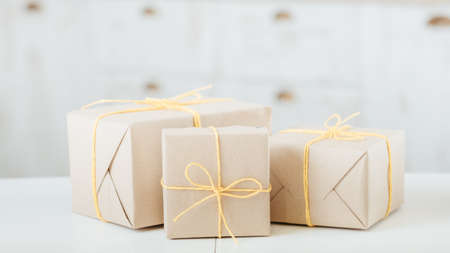 packages wrapped in craft paper. shop goods delivery. three boxes tied with yellow twine