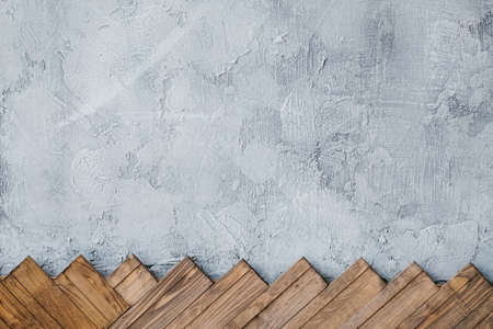 gray stucco plaster wall background. arranged row of wood planks at the bottom