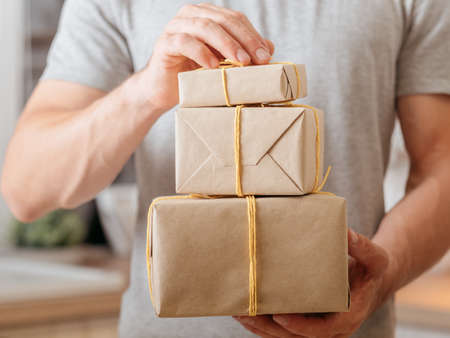 man holding stack of wrapped boxes for delivery. online order shipping serviceの写真素材
