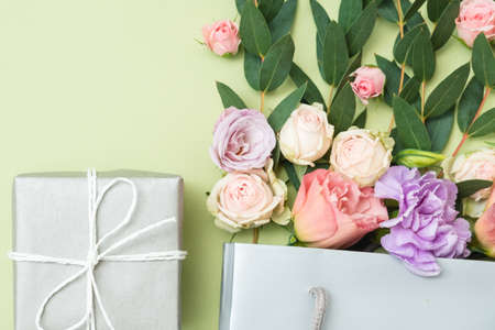 Present delivery. Gift box and rose bouquet on green background. Flat lay.の写真素材