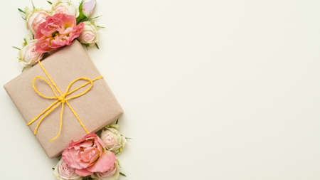 Womens day present. Craft paper gift box. Floral decor. Free space on ivory background. Flat lay.の写真素材