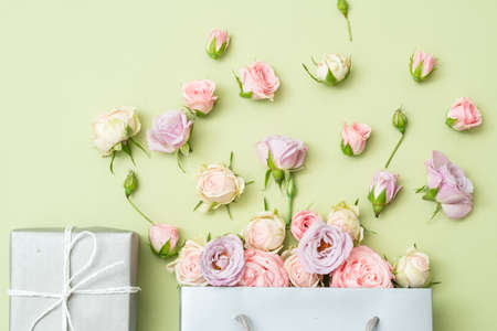 Mothers day present. Fresh roses bouquet and gift box on green background. Flat lay.の写真素材