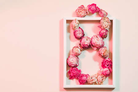 Womens day congratulation. Conceptual flower composition on pink background. 8 shaped roses in white...
