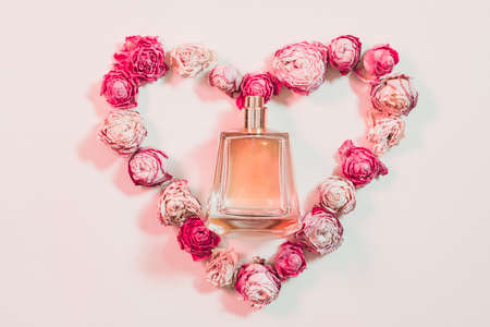 Valentines day gift. Greeting composition. Perfume and heart shaped dried roses on ivory background.の写真素材