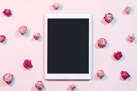 Blogging and social networks. Tablet computer with black screen on pink rose background. Flat lay.の写真素材