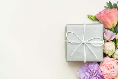 Present delivery. Silver gift box. Festive flower decor. Copy space on ivory background. Top view.の写真素材