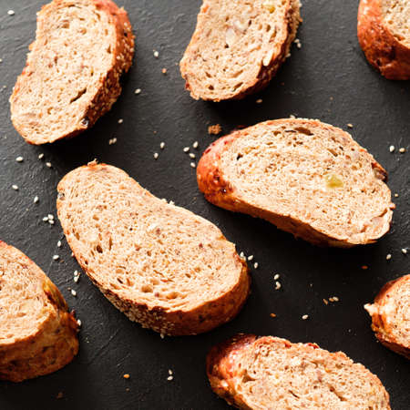 Brown bread slices on black background close up. Bread bakery concept.