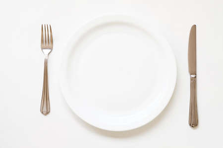 Dinner place setting. Empty porcelain plate with cutlery on white background.の写真素材