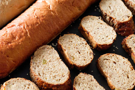 Bakery business close up. Baguette and wholegrain bread slices background.