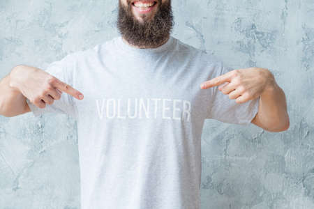 Volunteering activity. Modern lifestyle concept. Man in tshirt pointing at volunteer sign.の写真素材