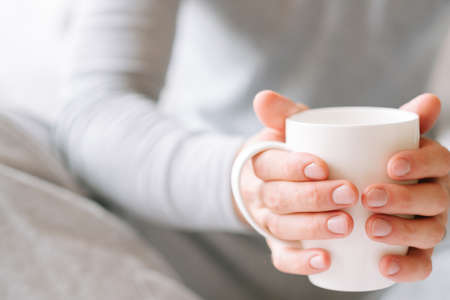 Morning coziness. Man in pyjamas holding white cup of favorite drink.