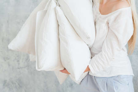 Quality bedding. Sound sleep concept. Woman holding pile of pillows.