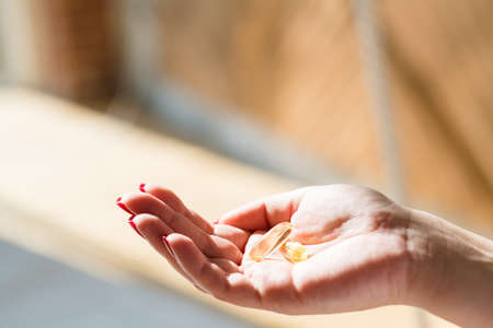 Spring vitamin deficiency. Woman hand holding fish oil supplement.の写真素材