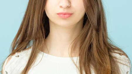 Female plumpy lips. Beauty concept. Girl with long brown hair and clean fresh skin looking toward...
