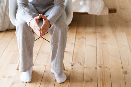 Taking decision. Man in pyjamas sitting in white chair with steepling hands.