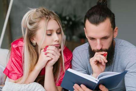 Family morning ritual. Work day planning. Man and woman in bed making notes.の写真素材