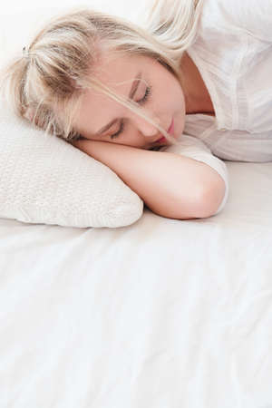 Morning bedtime. Rest and relaxation concept. Young blonde woman sleeping peacefully in bed.