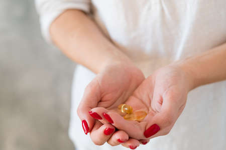 Female health and vitamin deficiency. Woman holding fish oil supplements in hands.