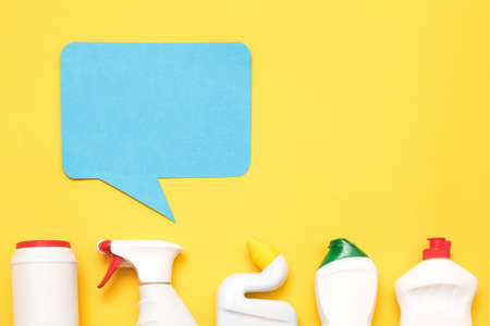 House cleaning supplies review. Row ofplastic bottles. Blue speech bubble on copy space.