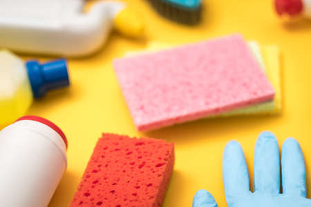 House cleaning products on yellow background. Defocused supplies variety.