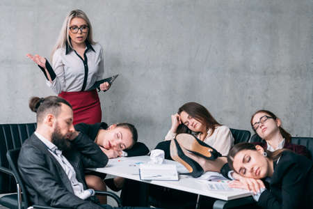 Overworking team. Annual business report. Astounded teamlead looking at colleagues sleeping at workplace.の写真素材