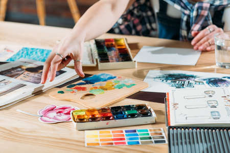 Artist workplace. Inspiration. Painter creating artwork with sketchbook and palette supplies around.の写真素材