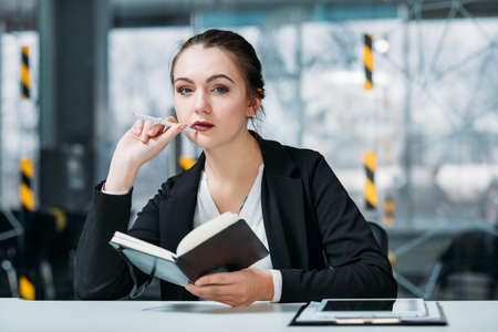 Corporate executive portrait. Business matters planning. Thoughtful manager with day planner at workplace.の写真素材
