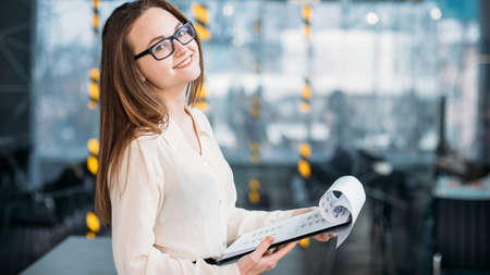Corporate analyst at workplace. Business diagrams analysis. Young attractive female in glasses with documents.の写真素材