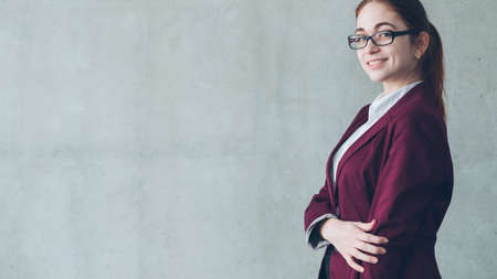 Young corporate employee portrait. Successful job interview. Smiling young female looking at camera. Copy space on grey background.の写真素材