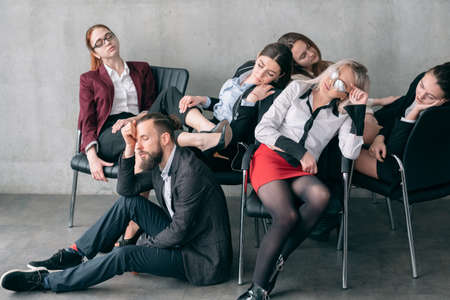 Annual audit. Overworking fatigue. Tired managers sleeping on chairs and floor.の写真素材
