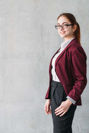 Business career start. Young smiling intern in glasses wearing formal outfit. Copy space on grey background.の写真素材