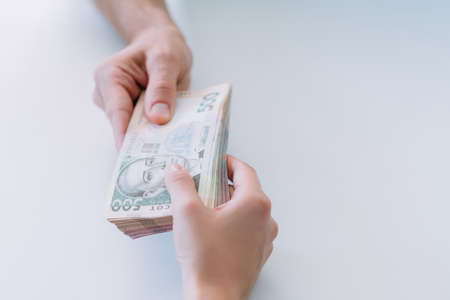 Cash payment. Man and woman hands. Batch of 500 ukrainian hryvnia bills. Copy space on white background.の写真素材