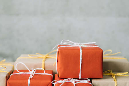 B2b sales. Online order. Shopping delivery. Parcel stack wrapped in red and craft paper. Copy space on grey background.の写真素材