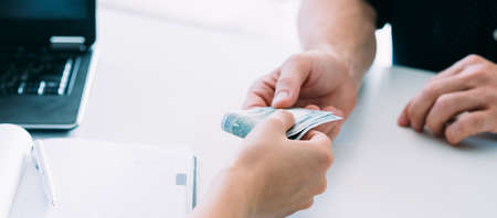 Cash money. Business corruption. Illegal compensation. Dollar bills bribe in man and woman hands.